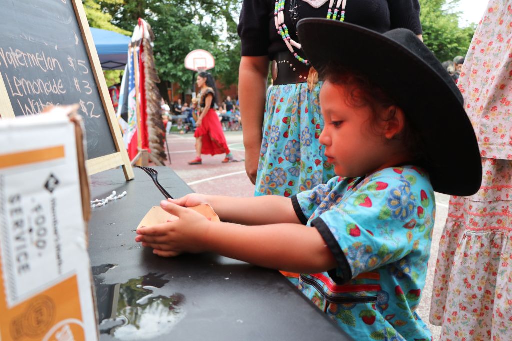 little boy at a powwow  takes food from a vendor 